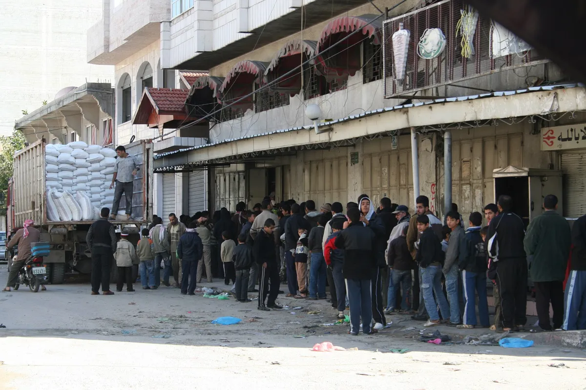 Palestinians queue for bread as a truck delivers flour in Gaza